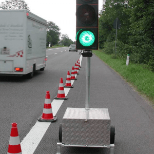 Cones placed along the road, a stoplight, and a mix of trucks and cars on the road